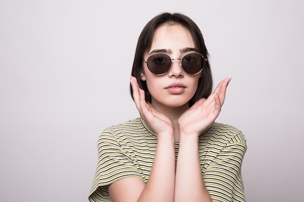 Model mit kurzen Haaren. Junges Mädchen in der Sonnenbrille mit den Händen nahe Gesicht, das aufwirft