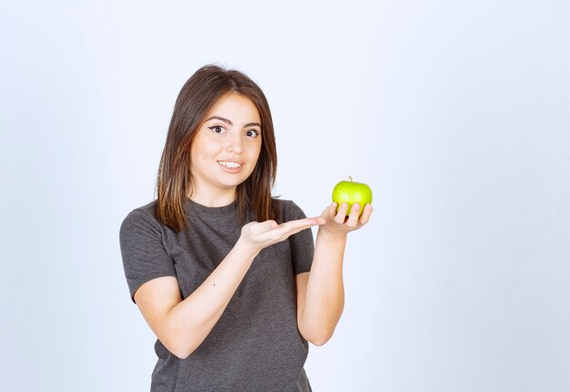 Modell der jungen Frau, das an einem grünen Apfel zeigt