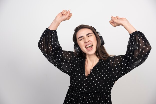 Modell der jungen Frau, die Musik in den Kopfhörern tanzt und hört