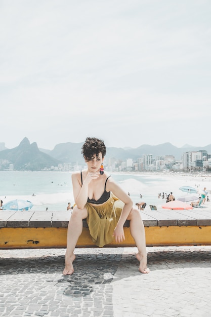 Modell des gelockten Haares, das ein Abendkleid trägt und auf der Promenade in Rio de Janeiro aufwirft