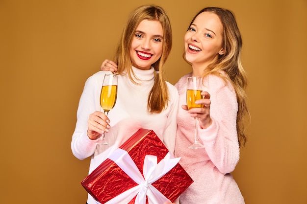 Modelle mit großer Geschenkbox, die Champagner in Gläsern trinken, die Neujahr feiern