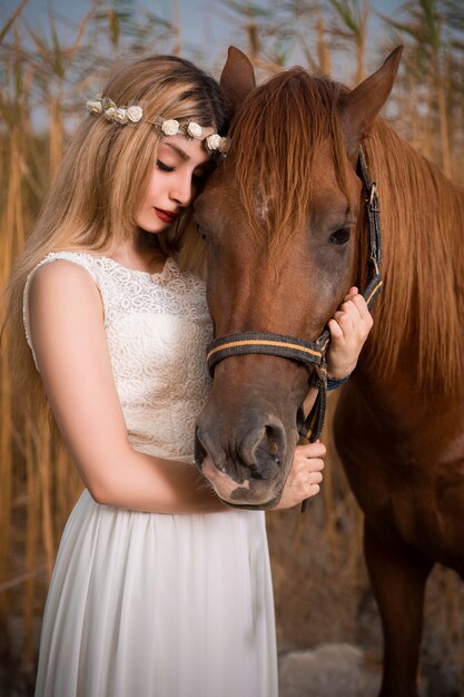 Modemodell im weißen Kleid, das mit einem Pferd aufwirft