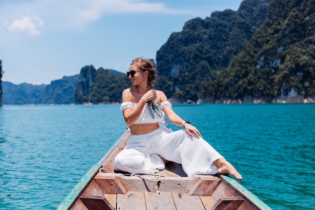 Modeporträt der jungen Frau im weißen Oberteil und in den Hosen im Urlaub, auf dem Segeln des thailändischen Holzboots. Reisekonzept. Frau im Khao Sok Nationalpark.