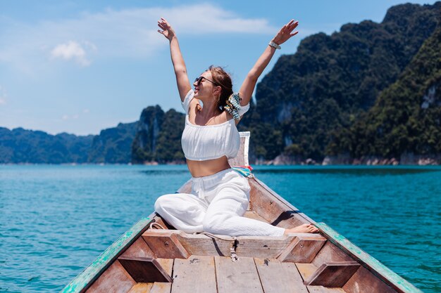 Modeporträt der jungen Frau im weißen Oberteil und in den Hosen im Urlaub, auf dem Segeln des thailändischen Holzboots. Reisekonzept. Frau im Khao Sok Nationalpark.