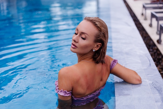 Kostenloses Foto modeporträt der kaukasischen frau im bikini im blauen schwimmbad im urlaub am tageslicht des tages