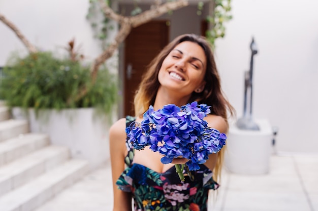 Modeporträt der kaukasischen frau im stilvollen sommeroverall mit blumen außerhalb der villa