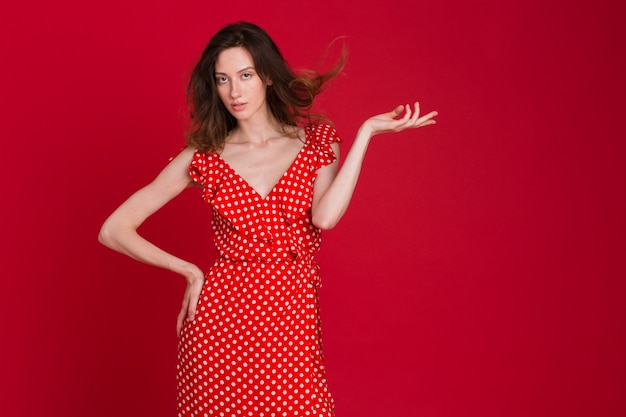 Modeporträt der lächelnden jungen Frau im rot gepunkteten Kleid auf Rot