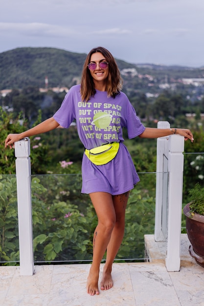 Modeporträt stilvolle junge europäische fit gebräunte Frau im lila langen Hemd