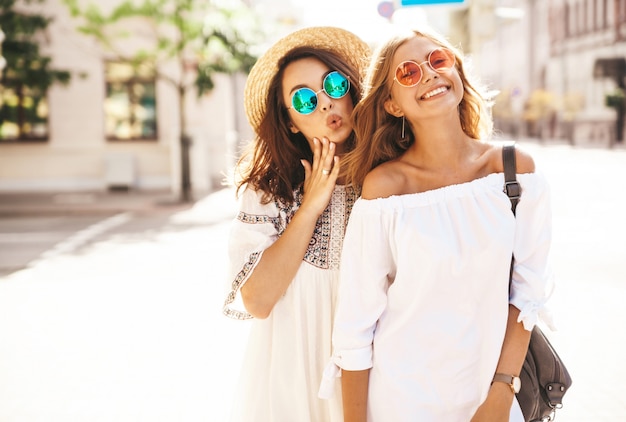 Modeporträt von zwei jungen stilvollen Hippie-Brünetten- und blonden Frauenmodellen im sonnigen Sommertag in der weißen Hipster-Kleidung, die aufwirft. Werde verrückt