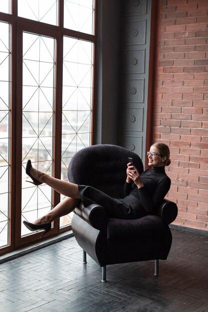 Moderne Frau auf Couch unter Verwendung des Mobiles