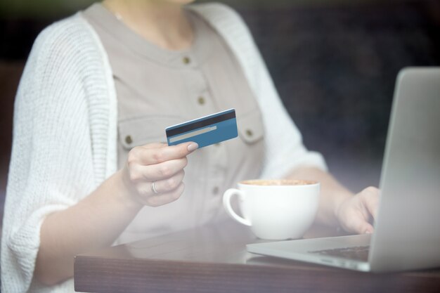 Moderne Frau bezahlt online mit Kreditkarte. Schuss durch Fenster