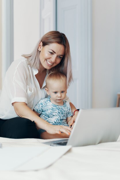 Moderne Frau, die mit Kind arbeitet. Multitasking-, Freiberufler- und Mutterschaftskonzept