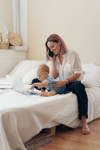 Moderne Frau, die mit Kind arbeitet. Multitasking-, Freiberufler- und Mutterschaftskonzept