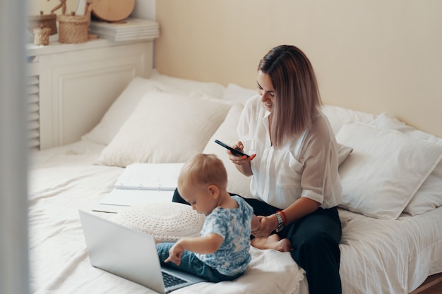 Moderne Frau, die mit Kind arbeitet. Multitasking-, Freiberufler- und Mutterschaftskonzept