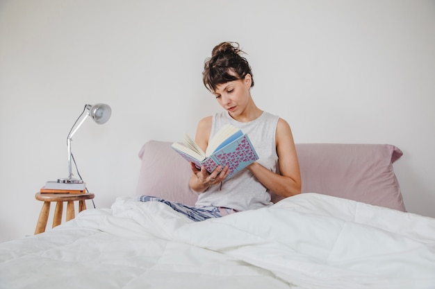 Moderne Frau im Bett mit Buch