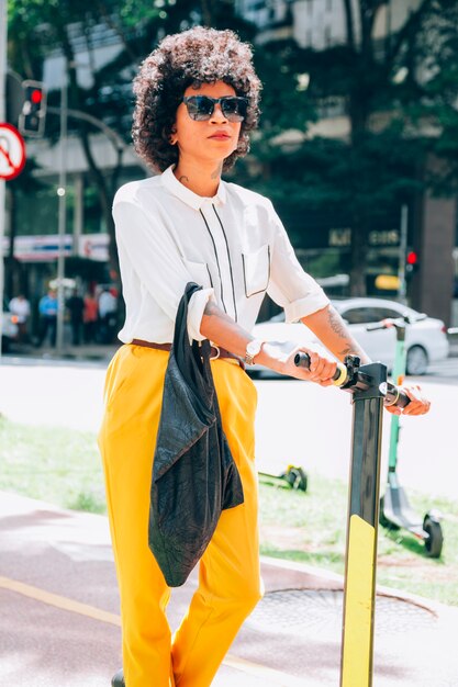 Moderne Frau in einer Stadt mit einem Elektroroller