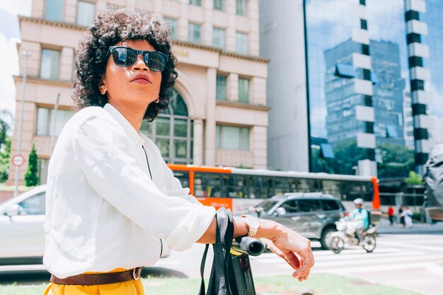 Moderne Frau in einer Stadt mit einem Elektroroller