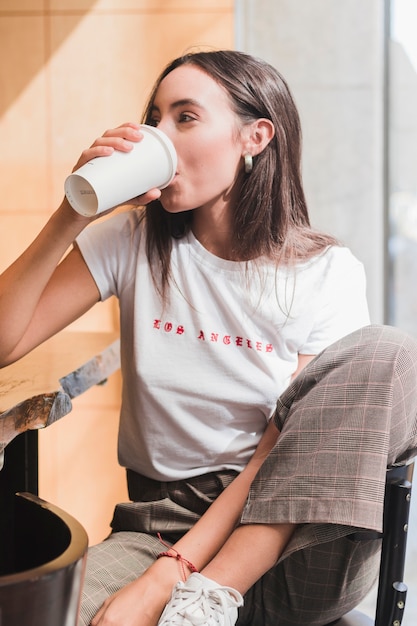 Kostenloses Foto moderne junge frau, die im café trinkt den kaffee sitzt