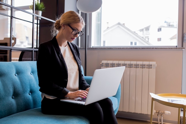 Moderne junge Geschäftsfrau, die Laptop im Büro verwendet