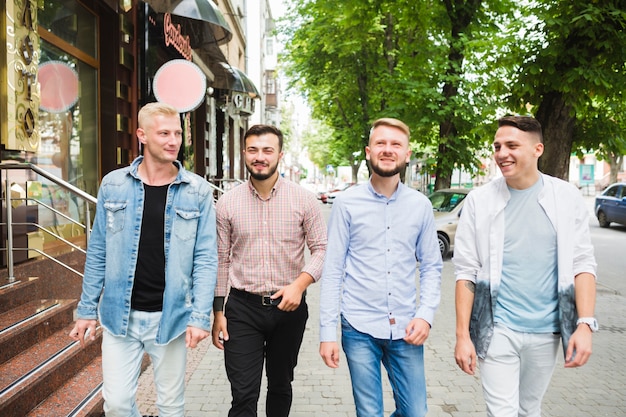 Moderne männliche Freunde, die zusammen auf Stadtstraße gehen