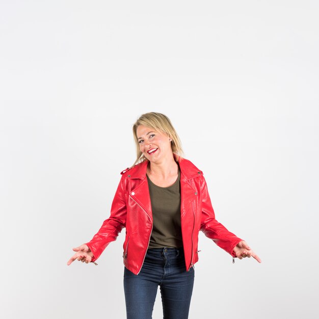 Moderne reife Frau in der roten Lederjacke, die gegen weißen Hintergrund steht