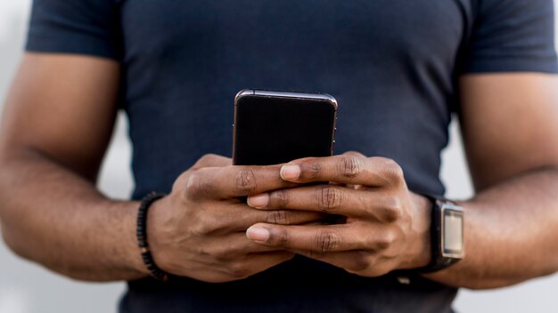 Moderner Afroamerikanermann, der sein Telefon prüft