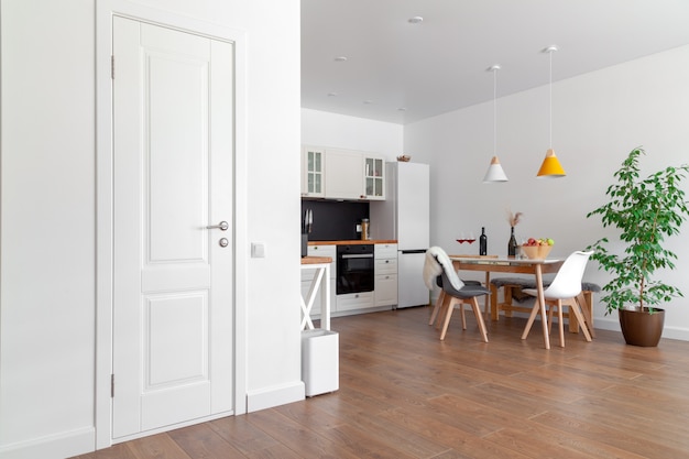 Moderner innenraum der küche, weiße wand, holzstühle, grüne blume im topf. konzept skandinavisches design Premium Fotos