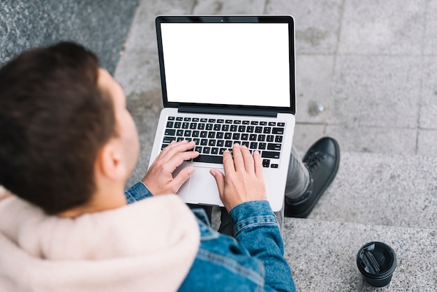 Moderner Mann, der Laptop in der städtischen Umwelt verwendet