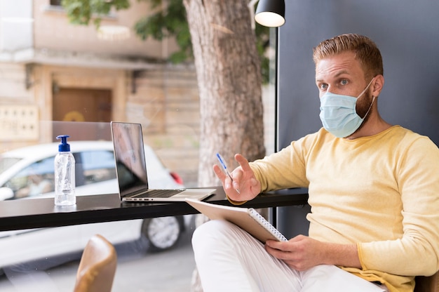 Moderner Mann, der unter Verwendung der medizinischen Maske arbeitet