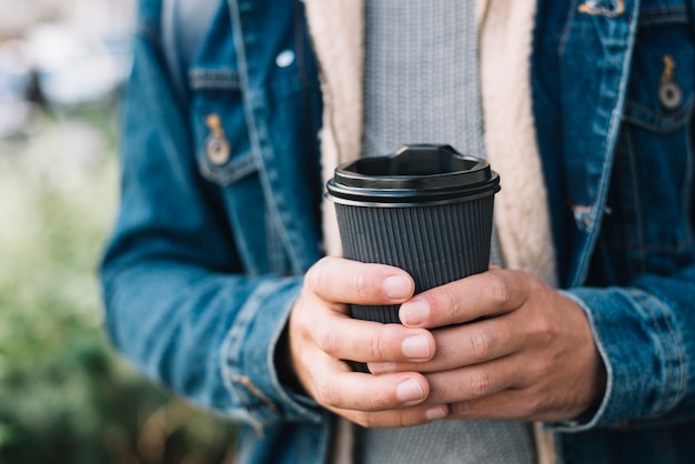 Moderner mann mit kaffeetasse in der städtischen umgebung