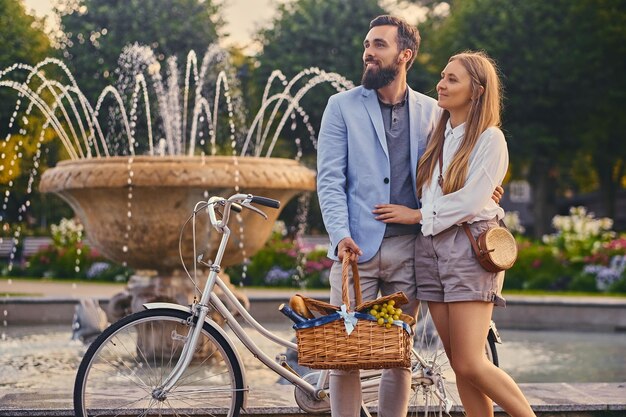 Modernes Paar mit Picknickkorb über Stadtbrunnenhintergrund.