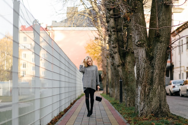 Modestraßenfotosession stilvoller junger Dame in einer grauen Kleidung