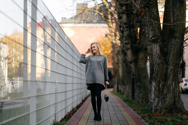 Modestraßenfotosession stilvoller junger Dame in einer grauen Kleidung