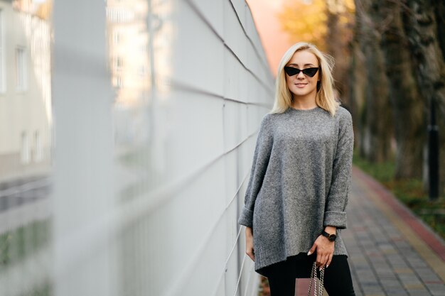 Modestraßenfotosession stilvoller junger Dame in einer grauen Kleidung