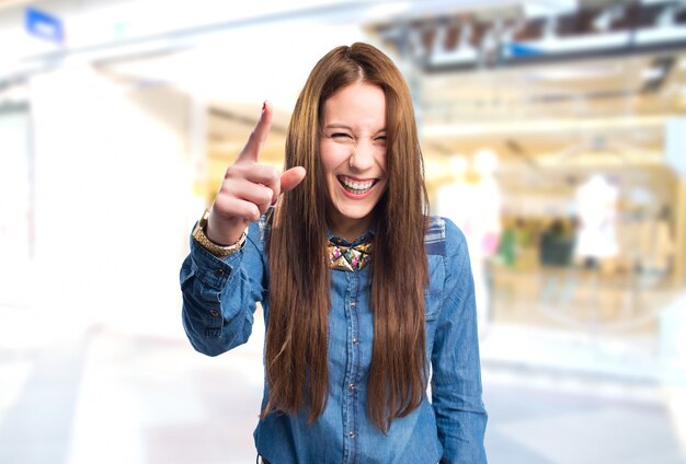 Modische junge Frau, die lustig mit ihrem Finger zeigt