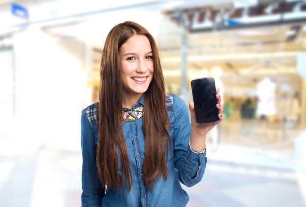 Modische junge Frau mit einem Smartphone zeigt