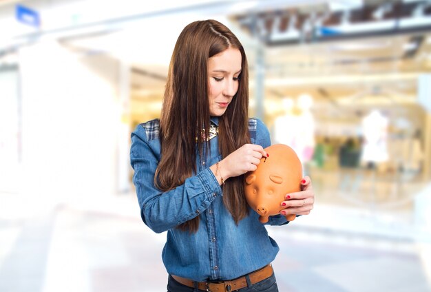 Modische junge Frau mit einem Sparschwein mit