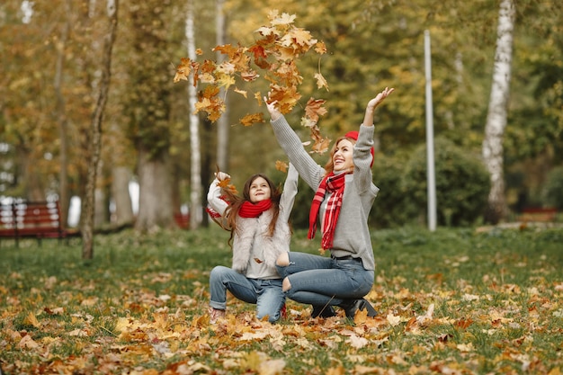 Modische Mutter mit Tochter. Gelber Herbst. Frau in einem roten Schal.