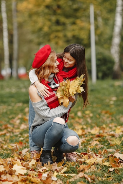 Modische Mutter mit Tochter. Gelber Herbst. Frau in einem roten Schal.