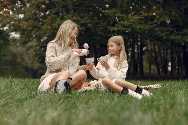 Modische Mutter mit Tochter. Leute sitzen auf einem Gras