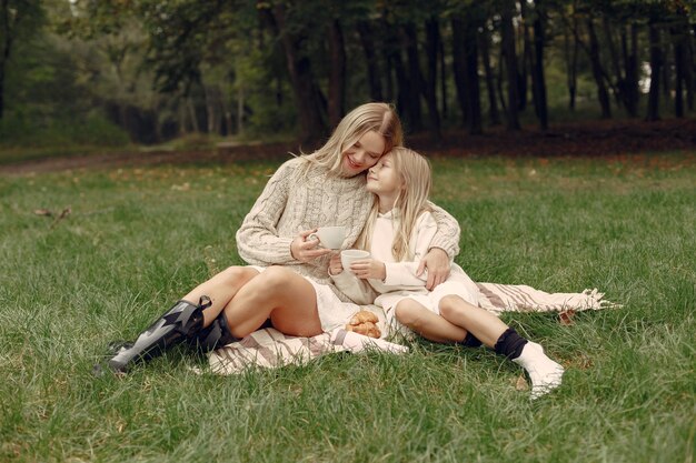 Modische Mutter mit Tochter. Leute sitzen auf einem Gras