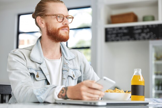 Modischer Hipster-Typ im Jeanshemd und mit stilvoller Brille