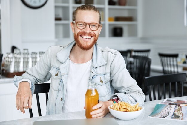 Modischer Hipster-Typ im Jeanshemd und mit stilvoller Brille