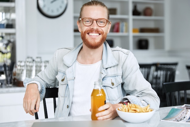 Modischer Hipster-Typ im Jeanshemd und mit stilvoller Brille