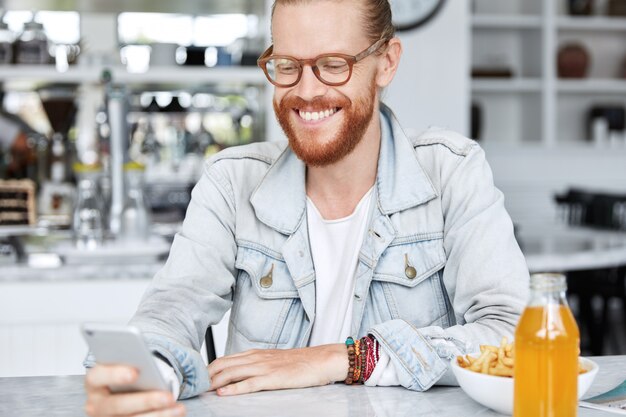 Modischer Hipster-Typ im Jeanshemd und mit stilvoller Brille