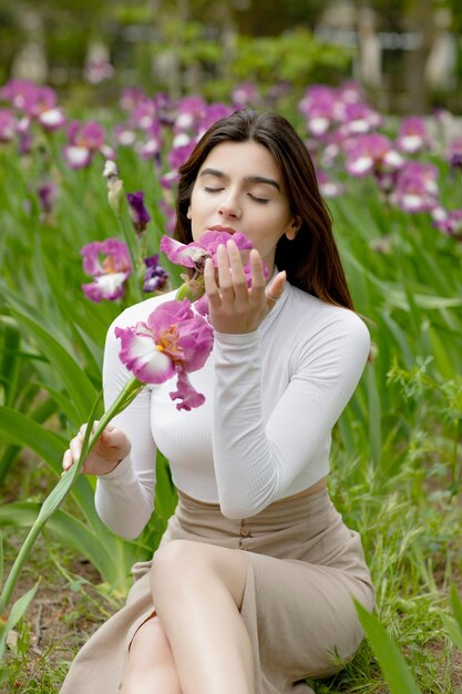 Modisches, schlankes Mädchen, das Blume riecht, mit geschlossenen Augen, die das Genießen bewundern