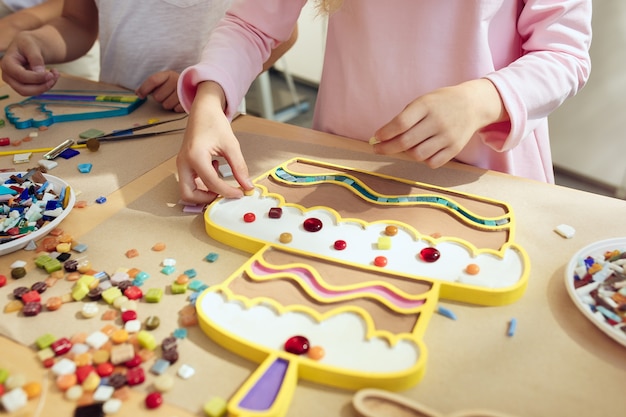 Mosaik-Puzzle-Kunst für Kinder, kreatives Spiel für Kinder. Hände spielen Mosaik am Tisch. Bunte mehrfarbige Details schließen.