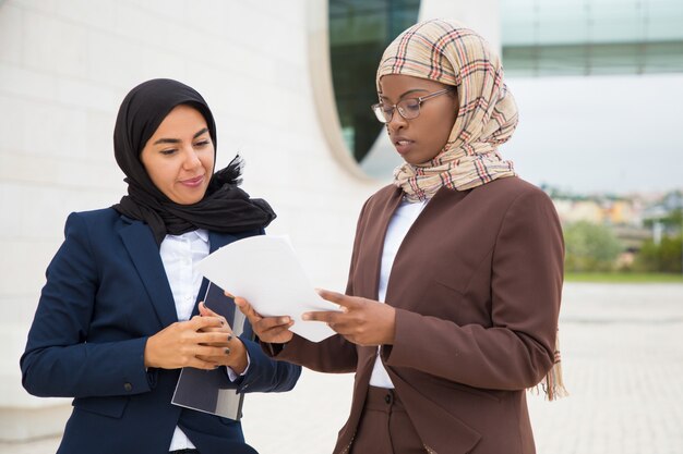 Moslemische Geschäftsfrauen, die Vertragstext besprechen