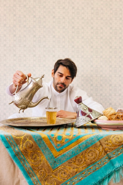 Moslemischer Mann, der auf Tabelle mit Tee sitzt