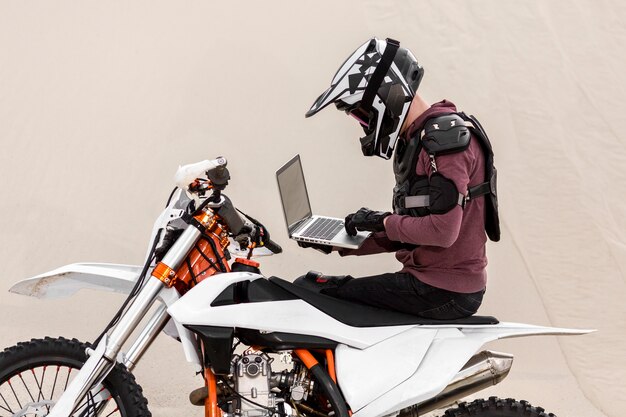 Motorradfahrer, der Laptop in der Wüste durchsucht